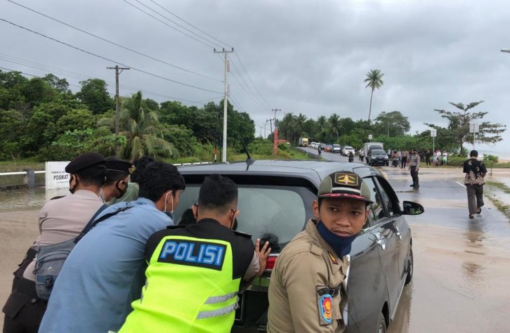 Personel Polres Bateng Bantu Pengendara Melewati Genangan Air Laut